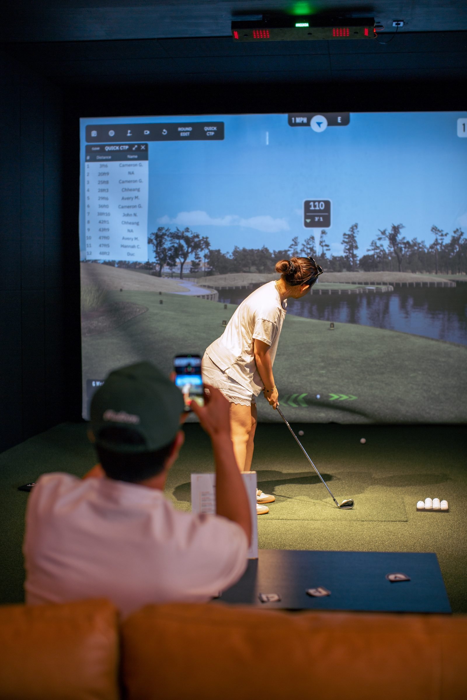 Golfer at top of the backswing in a simulator bay