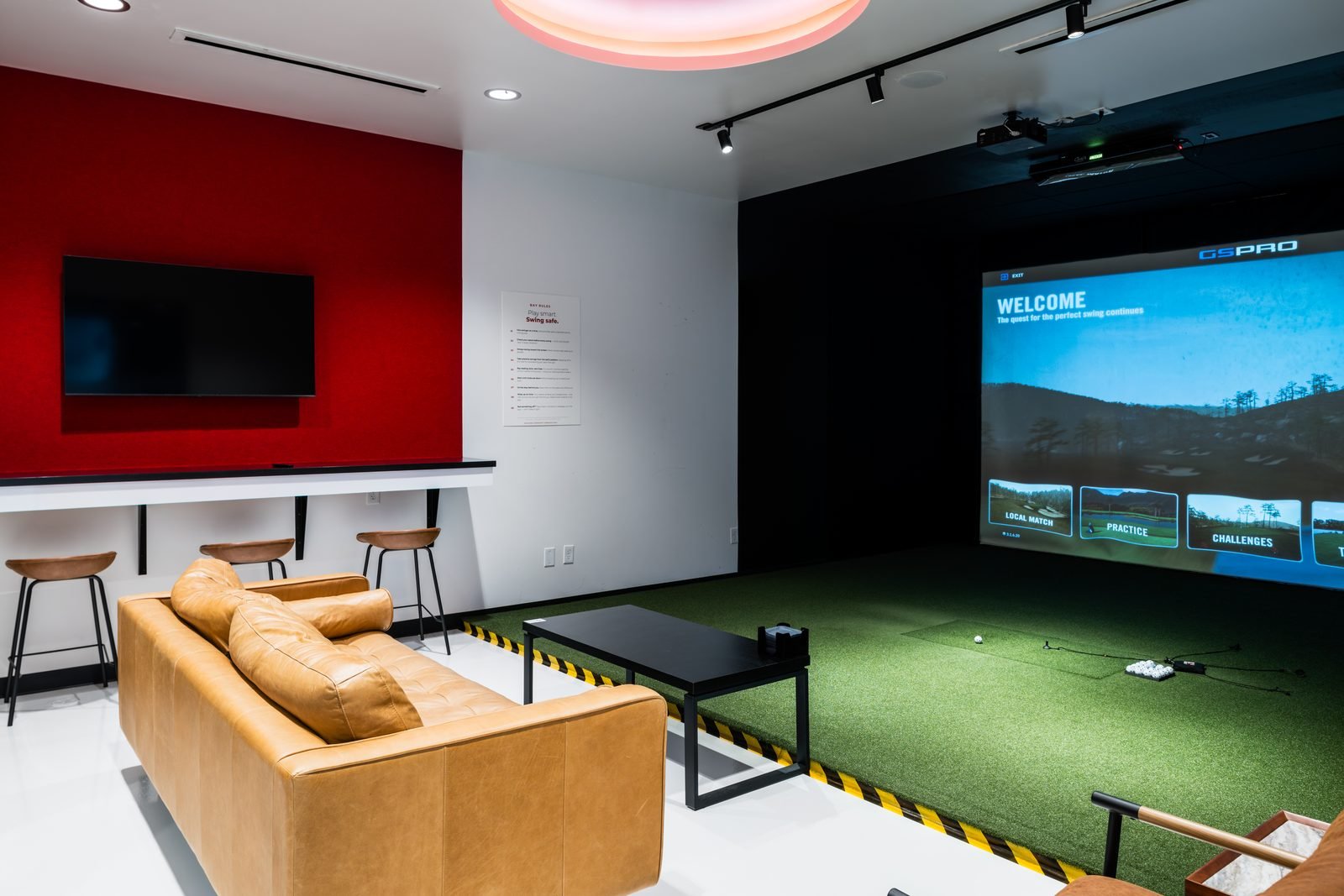 Private suite with a leather sofa, TV and red accent wall